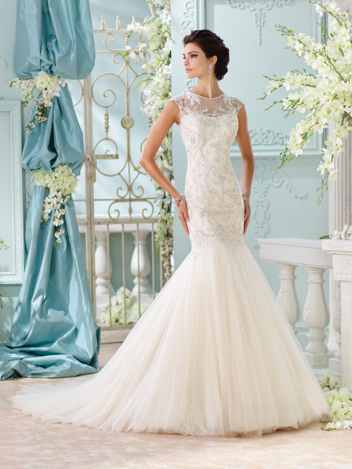 Vestido de Noiva com decote canoa e transparncia no colo e costas, corpo alongado em renda bordada em fio de seda e saia com corte sereia em camadas de tule francs e cauda.