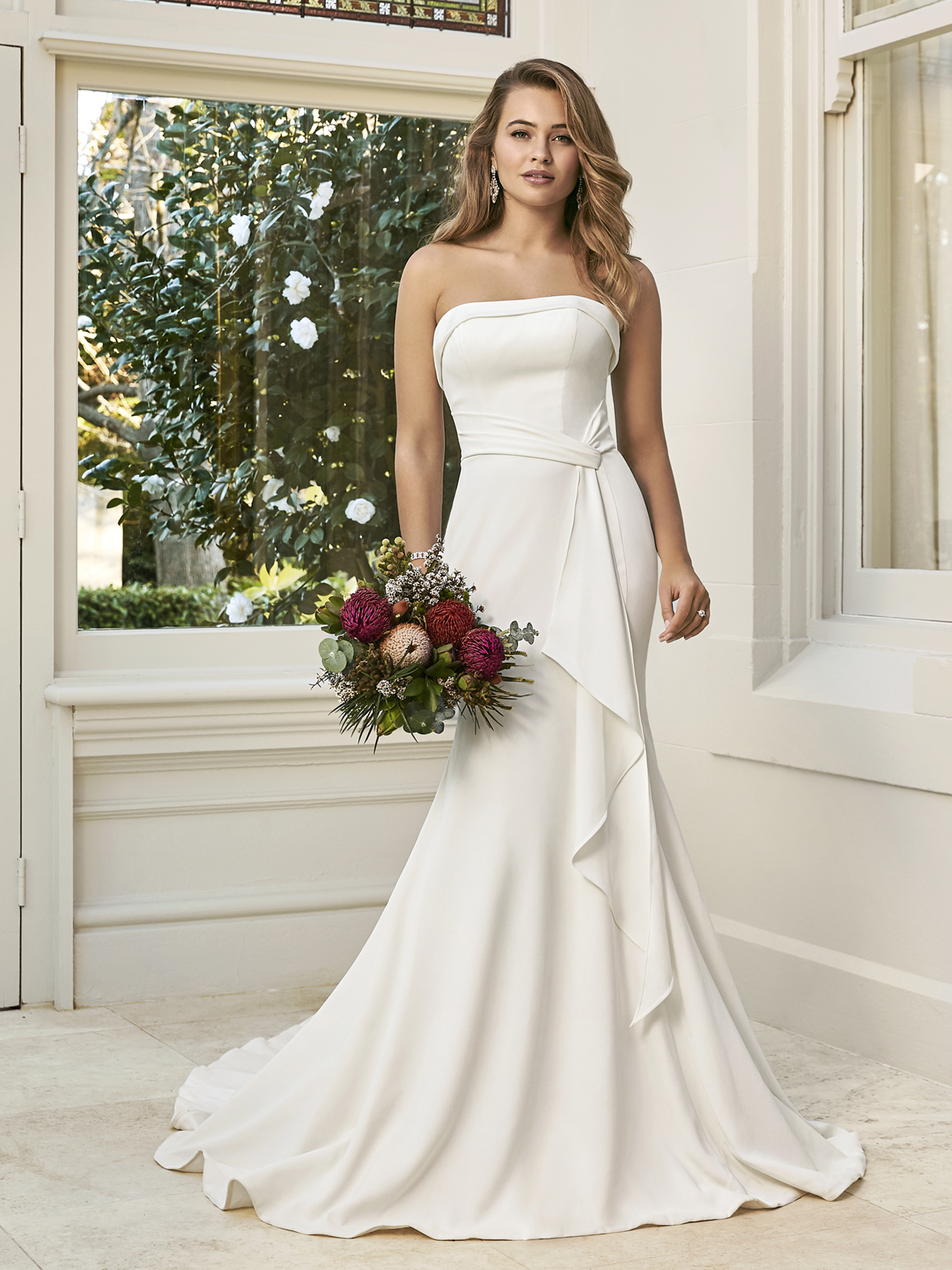 A imagem da elegncia moderna  esse vestido de noiva em crepe acetinado, uma silhueta de ajuste impecvel com decote tomara que caia, oferece um cinto drapeado que desce em cascata e um espartilho que completam o look minimalista e perfeito.